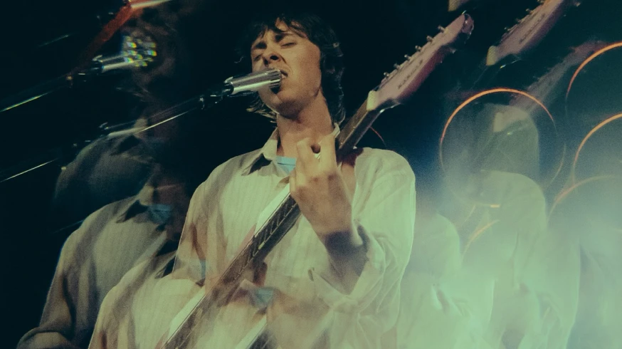 Musician performing live with Soyuz V1 microphone on stage in atmospheric lighting